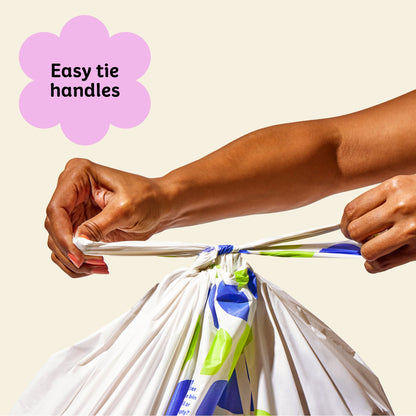 Two hands ties close Who Gives a Crap large recycled trash bag with the easy tie handles.