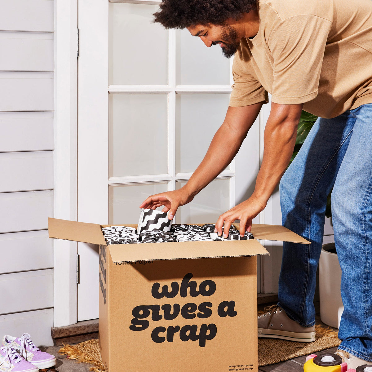 Person at door opening their Who Gives a Crap box of toilet paper.